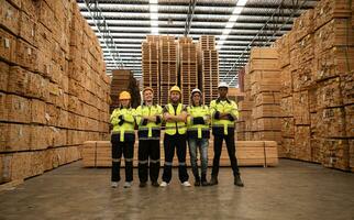 retrato de un grupo de trabajadores trabajo en un carpintería fábrica, en pie con brazos cruzado en un de madera depósito. foto