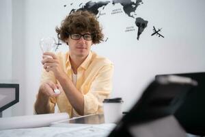 Young architect working on new project in his office He carries a light bulb that should not be used in buildings because it is not energy efficient and not earth-friendly. photo