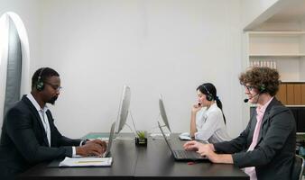 Group of business people wearing headset working actively in office. Call center, telemarketing, customer support agent provide service on telephone video conference call. photo