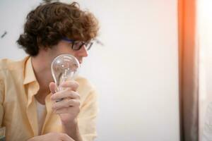 Young architect working on new project in his office He carries a light bulb that should not be used in buildings because it is not energy efficient and not earth-friendly. photo