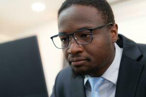 Serious African American businessman using laptop in office. This is a shallow depth of field photo