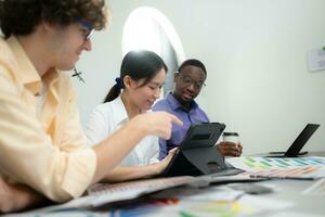 Multiethnic team of architects and designers are meeting to brainstorm design an application smartphone on a bright modern office working on a laptop. photo