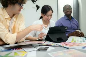 Multiethnic team of architects and designers are meeting to brainstorm design an application smartphone on a bright modern office working on a laptop. photo