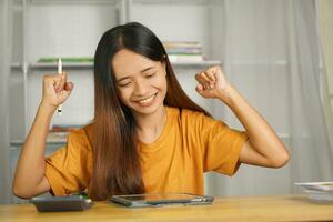 Asian woman working from home Happy from watching the profits through the computer. photo