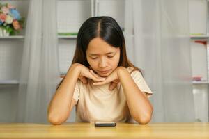 Woman using phone looking at investment profits at home office desk I miss the loss from investment. photo