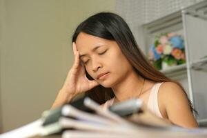 Asian woman working from home Tired of paperwork that is not completed on time photo