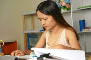 asiático mujer trabajando desde hogar cansado de papeleo ese es no terminado en hora foto