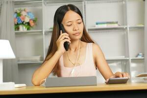 woman working at home Use your phone and computer to communicate with your teammates. photo