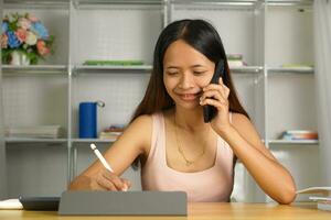 woman working at home Use your phone and computer to communicate with your teammates. photo