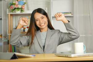 Happy businesswoman raising her hands in joy as she reached a business deal with a customer. photo