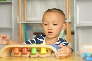 A boy plays with developmental toys on the table inside the house. photo