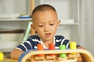 A boy plays with developmental toys on the table inside the house. photo