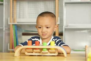 A boy plays with developmental toys on the table inside the house. photo