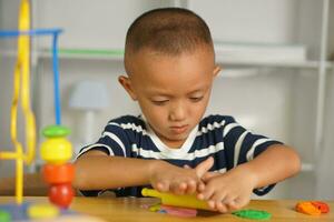 A boy kneads plasticine to make things soft. photo