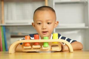 A boy plays with developmental toys on the table inside the house. photo