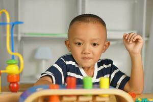 A boy plays with developmental toys on the table inside the house. photo