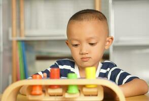 A boy plays with developmental toys on the table inside the house. photo