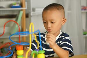 Boy playing with developmental toys on table at home photo