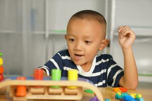 A boy plays with developmental toys on the table inside the house. photo