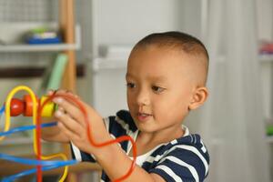 Boy playing with developmental toys on table at home photo