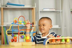 Boy playing with developmental toys on table at home photo