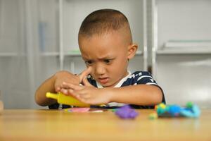 A boy kneads plasticine to make things soft. photo