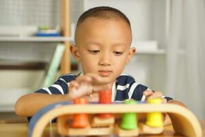 A boy plays with developmental toys on the table inside the house. photo