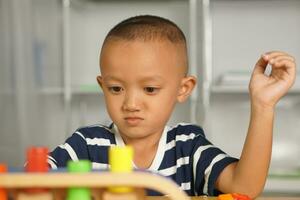 A boy plays with developmental toys on the table inside the house. photo