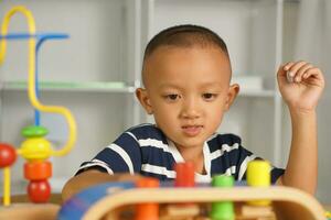 A boy plays with developmental toys on the table inside the house. photo