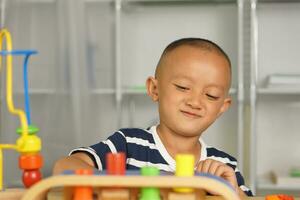 A boy plays with developmental toys on the table inside the house. photo