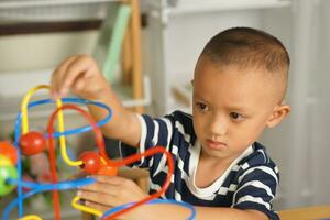 Boy playing with developmental toys on table at home photo