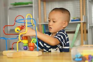 Boy playing with developmental toys on table at home photo