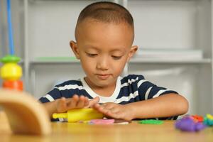 A boy kneads plasticine to make things soft. photo