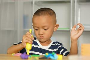 Boy making plasticine to promote development on the table in the house. photo