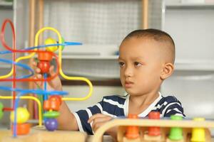 Boy playing with developmental toys on table at home photo