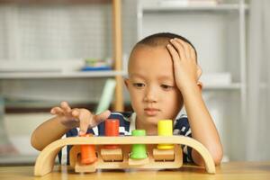 A boy plays with developmental toys on the table inside the house. photo