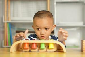 A boy plays with developmental toys on the table inside the house. photo
