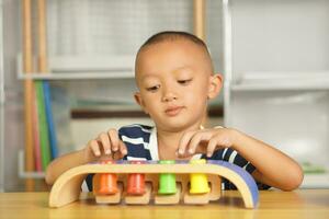 A boy plays with developmental toys on the table inside the house. photo