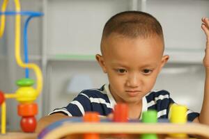 A boy plays with developmental toys on the table inside the house. photo