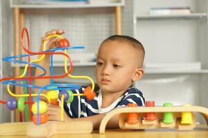 Boy playing with developmental toys on table at home photo