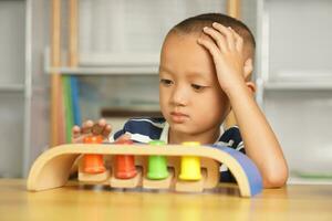 A boy plays with developmental toys on the table inside the house. photo