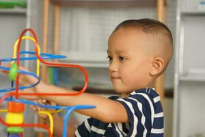 Boy playing with developmental toys on table at home photo