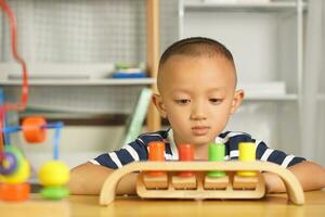 A boy plays with developmental toys on the table inside the house. photo