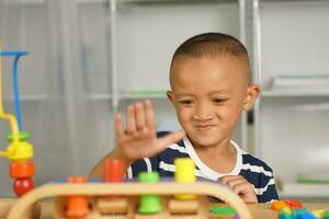 A boy plays with developmental toys on the table inside the house. photo