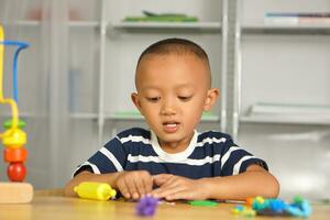 Boy making plasticine to promote development on the table in the house. photo