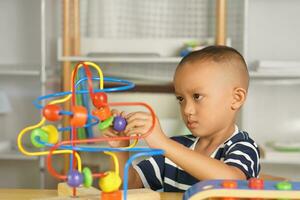 Boy playing with developmental toys on table at home photo