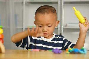 Boy making plasticine to promote development on the table in the house. photo