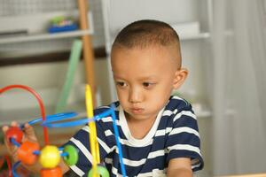 Boy playing with developmental toys on table at home photo