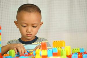 Asian boy playing with educational toys There are many beautiful colors on the table in the house. photo