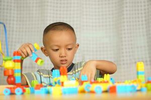 Asian boy playing with educational toys There are many beautiful colors on the table in the house. photo